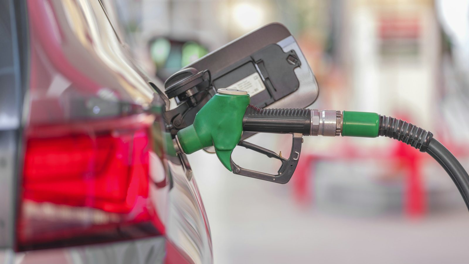 Pistolet de pompe vert inséré dans le réservoir d'une voiture, en station-service