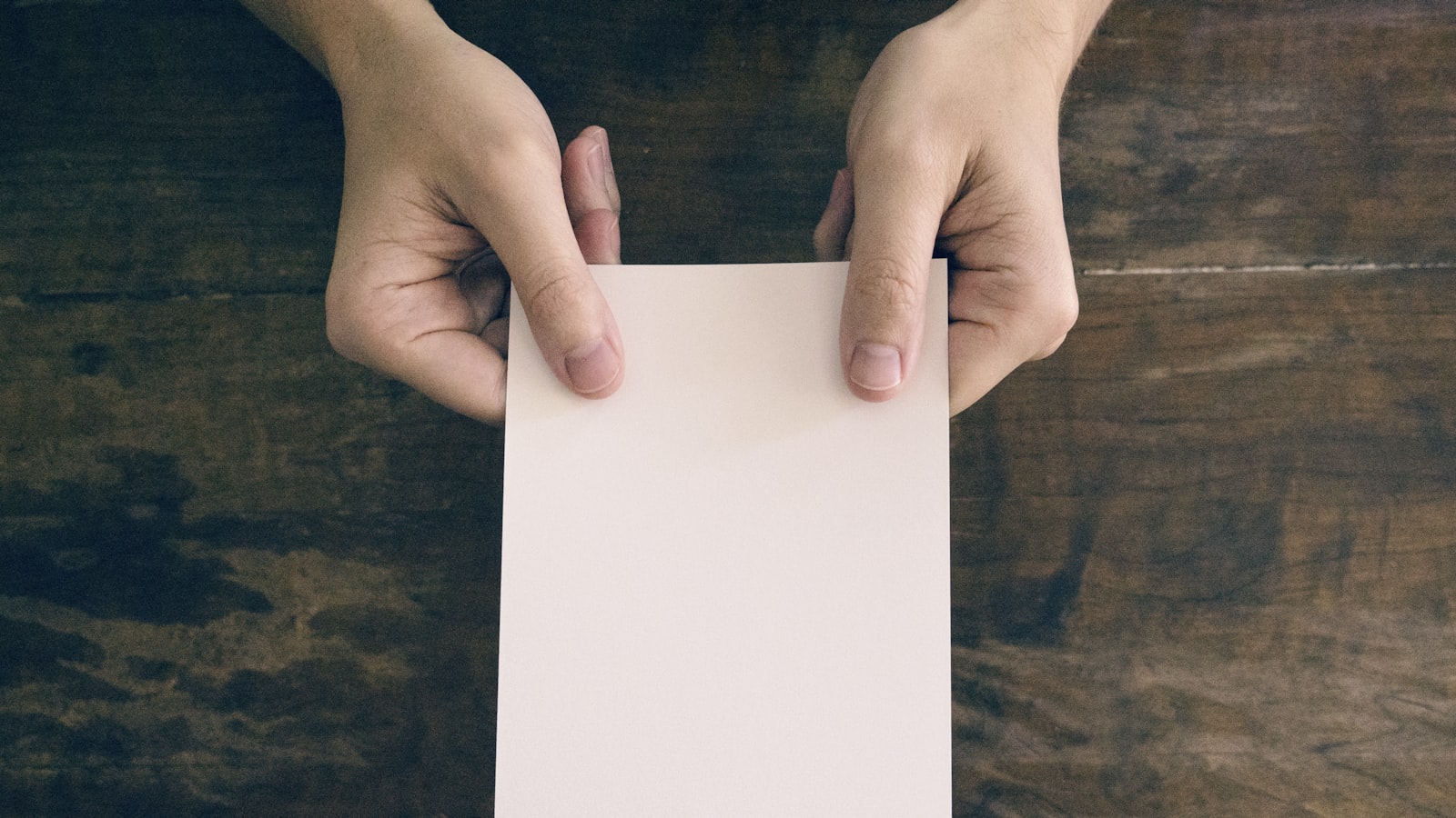 Mains tenant une feuille de papier dans la lumière