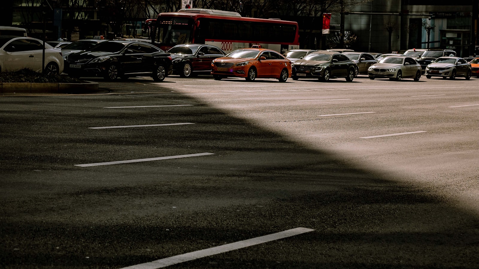 Grand parking aux places matérialisées au sol, avec des voitures rangées côte à côte en arrière-plan