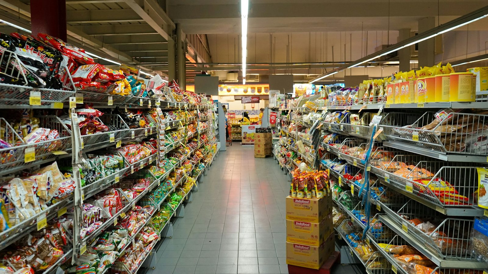 Allée de supermarché bordée de rayonnages remplis de produits alimentaires