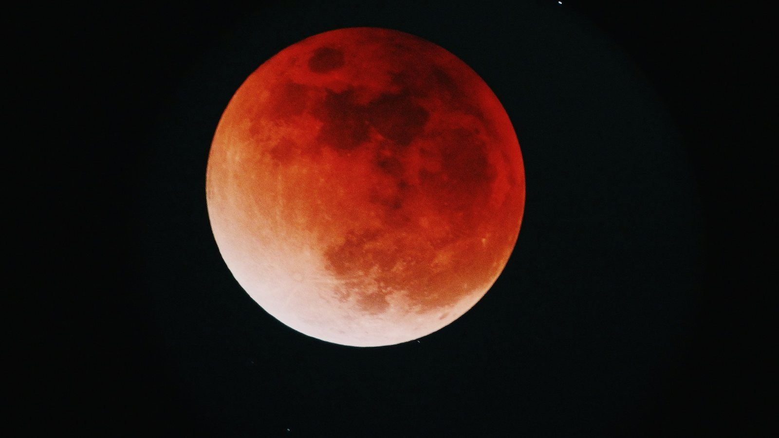 Lune partiellement plongée dans l'ombre de la Terre, basse au-dessus d'un horizon dégagé