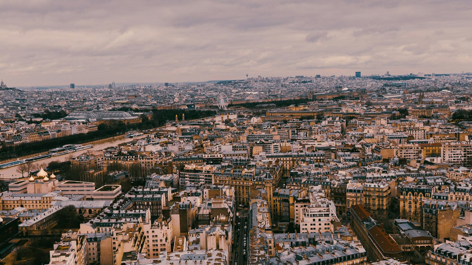 Vue aérienne d'une ville dense aux toits clairs qui s'étend jusqu'à l'horizon, sous un ciel couvert de fin de nuit