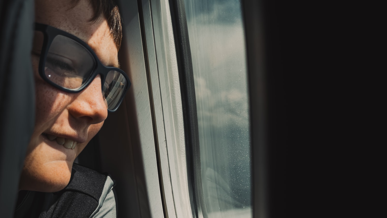Enfant portant des lunettes regardant par la fenêtre d'une voiture