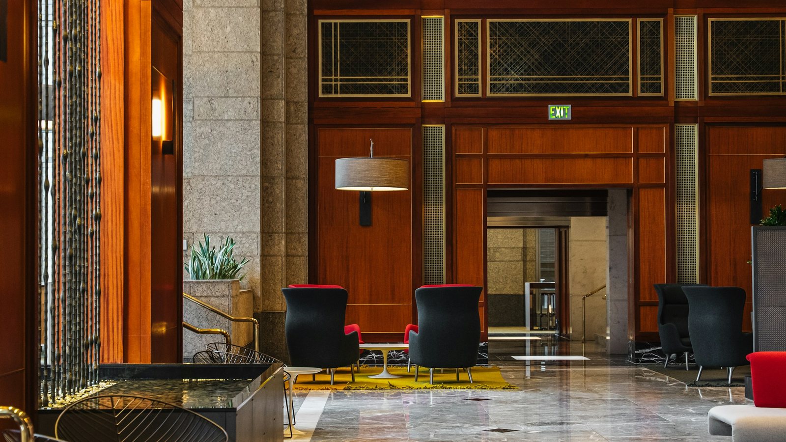 Hall d'hôtel de luxe désert, boiseries sombres, fauteuils et sol en marbre
