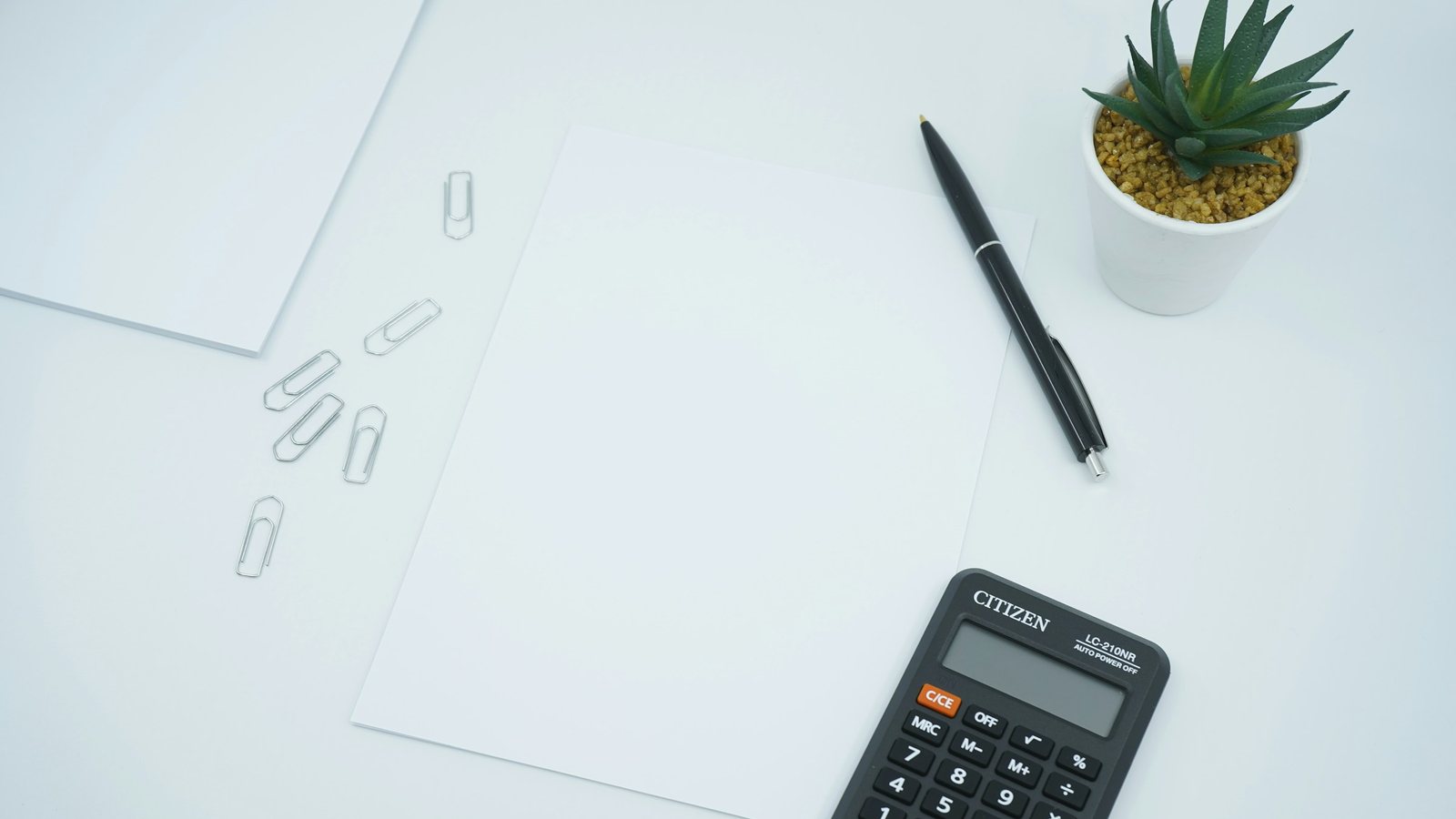 Une calculatrice noire à côté d'un stylo
