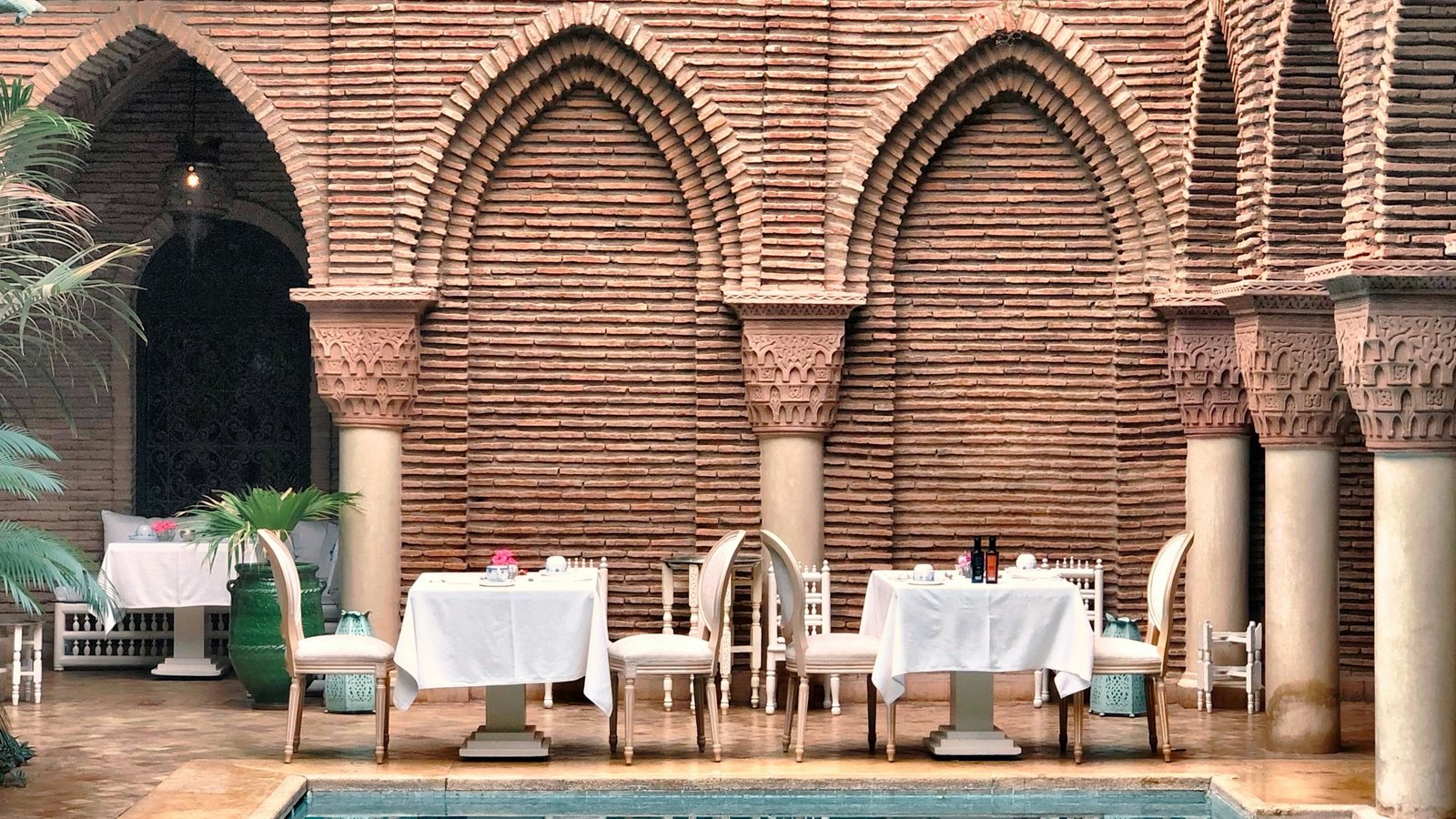 Des chaises en céramique au bord d'une piscine de riad