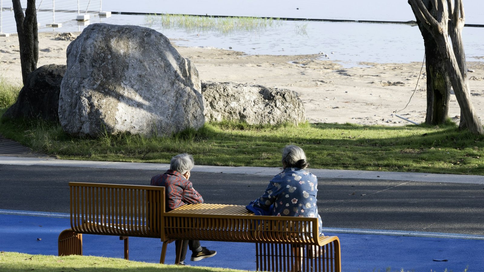 Deux personnes âgées assises sur un banc face à l'eau