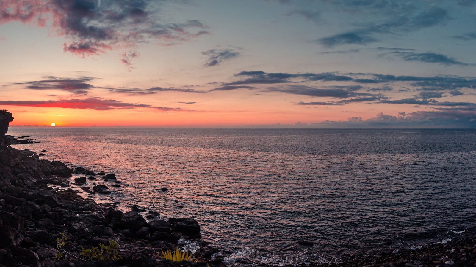 Le soleil se couchant sur l'océan depuis une falaise
