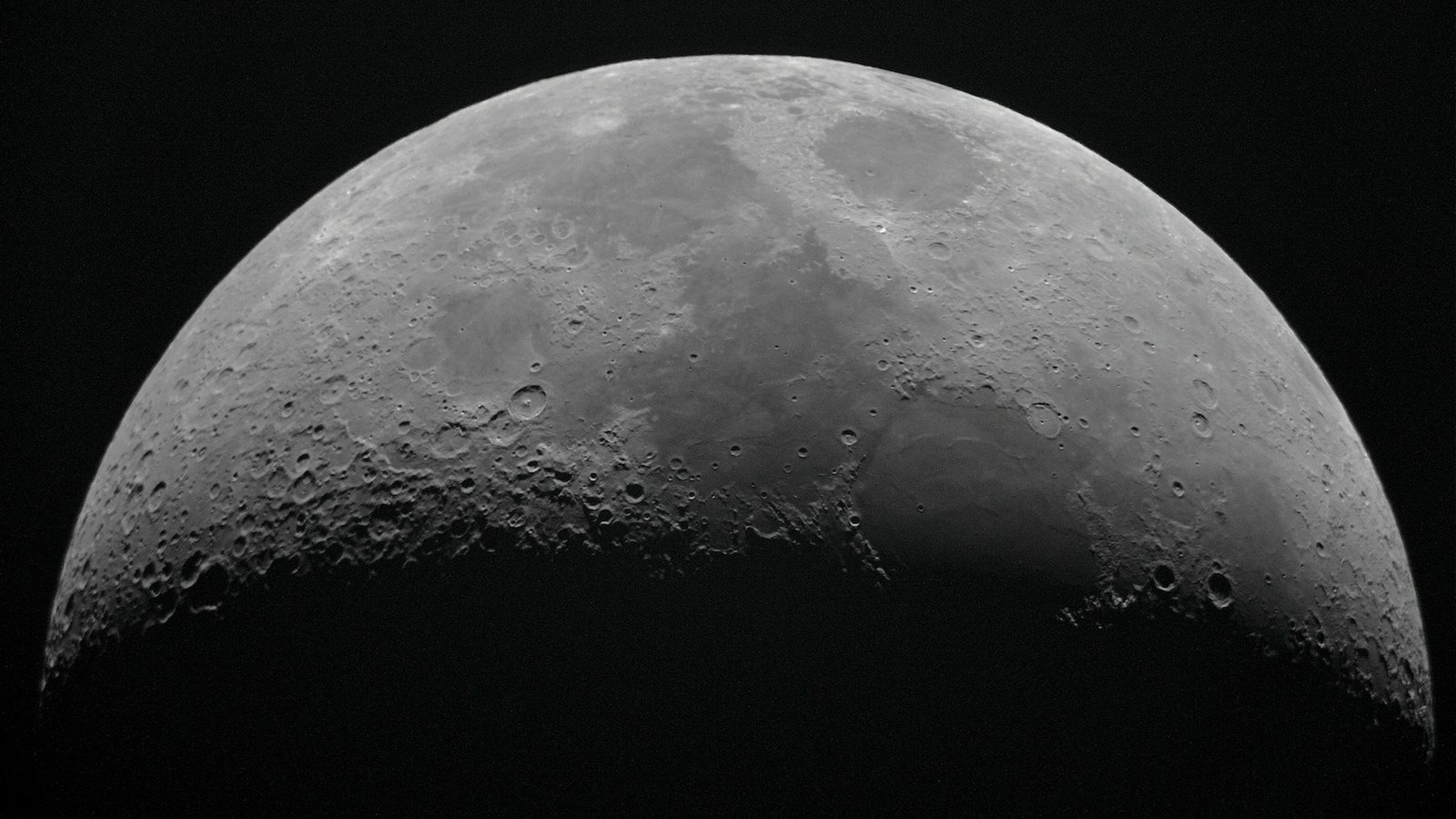 Gros plan de la Lune photographié au téléobjectif, cratères et mers lunaires visibles sur un ciel noir