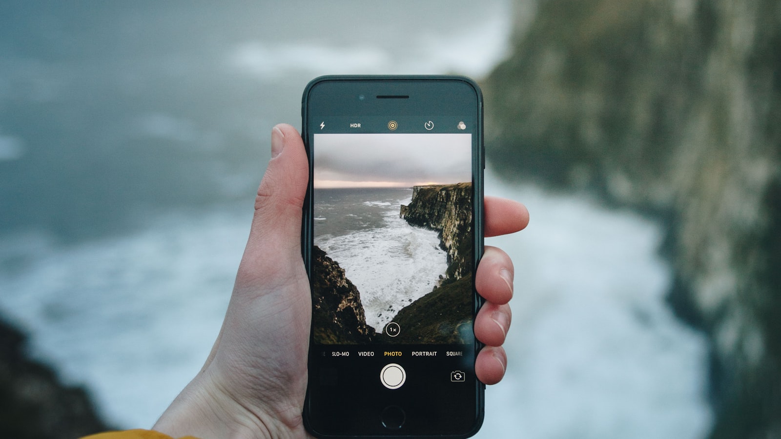 Main photographiant un paysage au smartphone