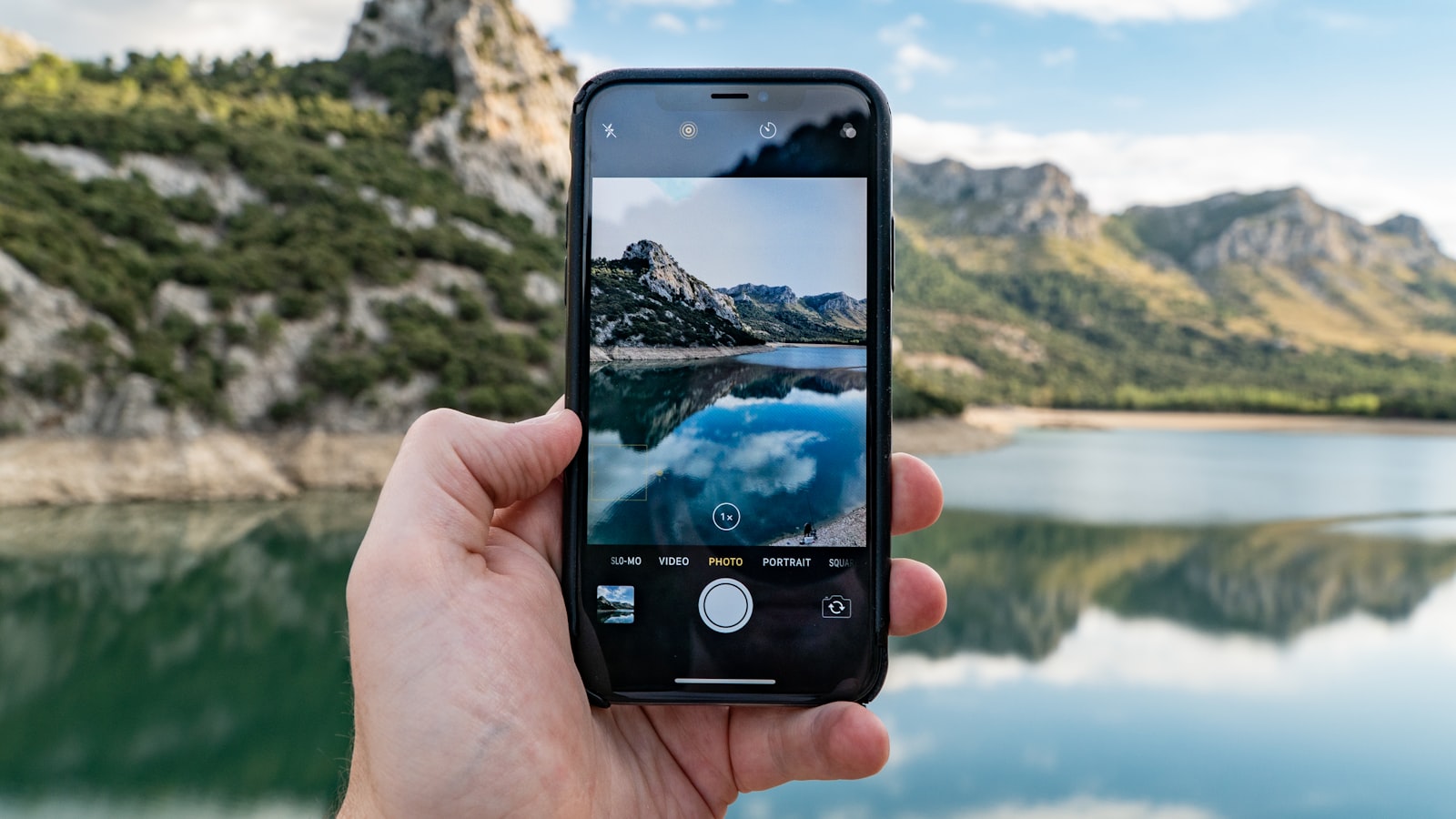 Main tenant un smartphone qui photographie le ciel