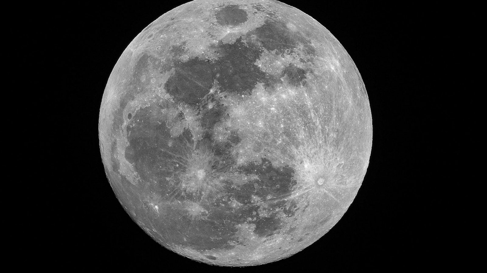 Smartphone tenu à bout de bras face à la Lune basse sur l'horizon, le disque lunaire partiellement plongé dans l'ombre