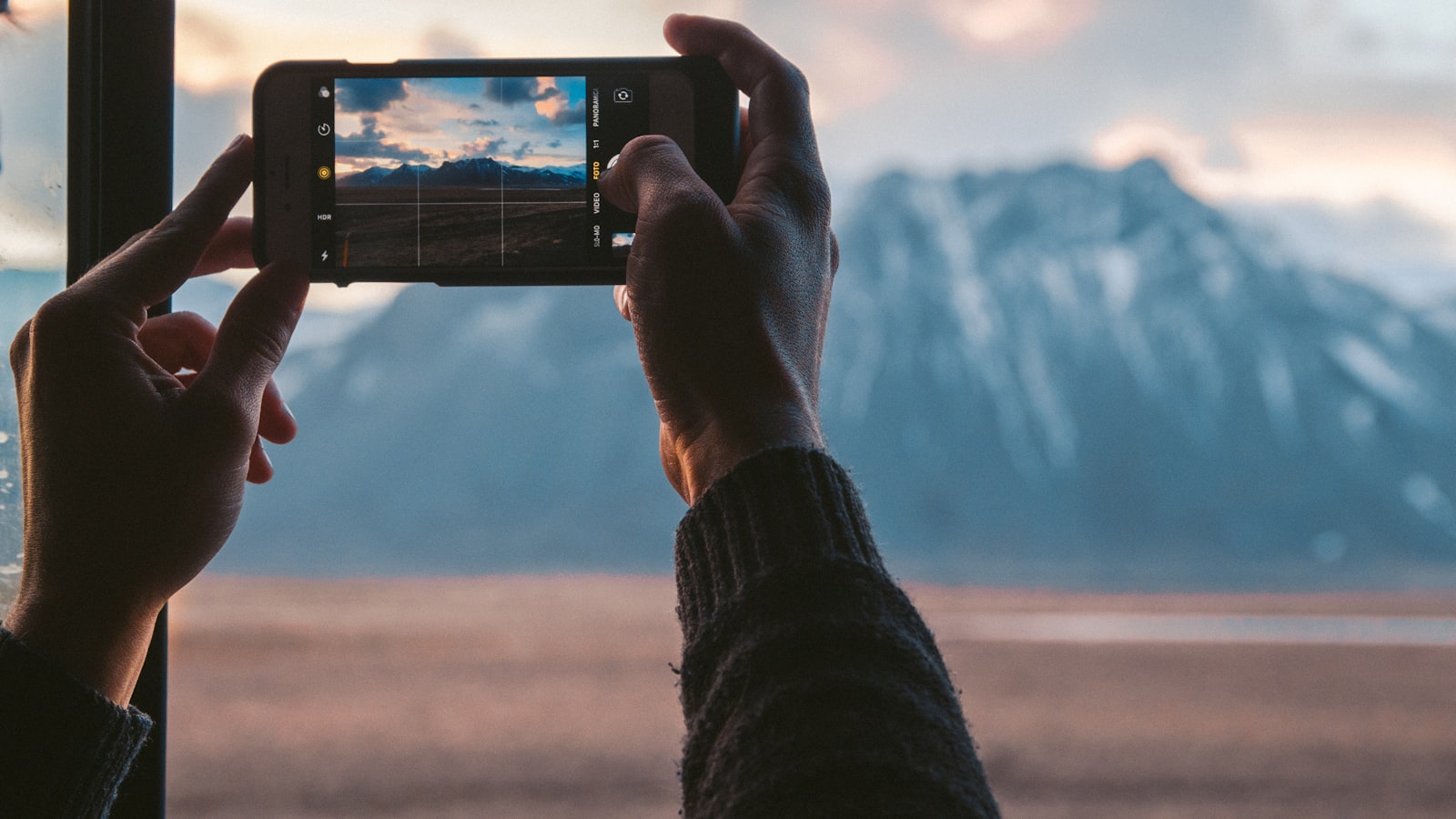 Mains photographiant le ciel en montagne au smartphone