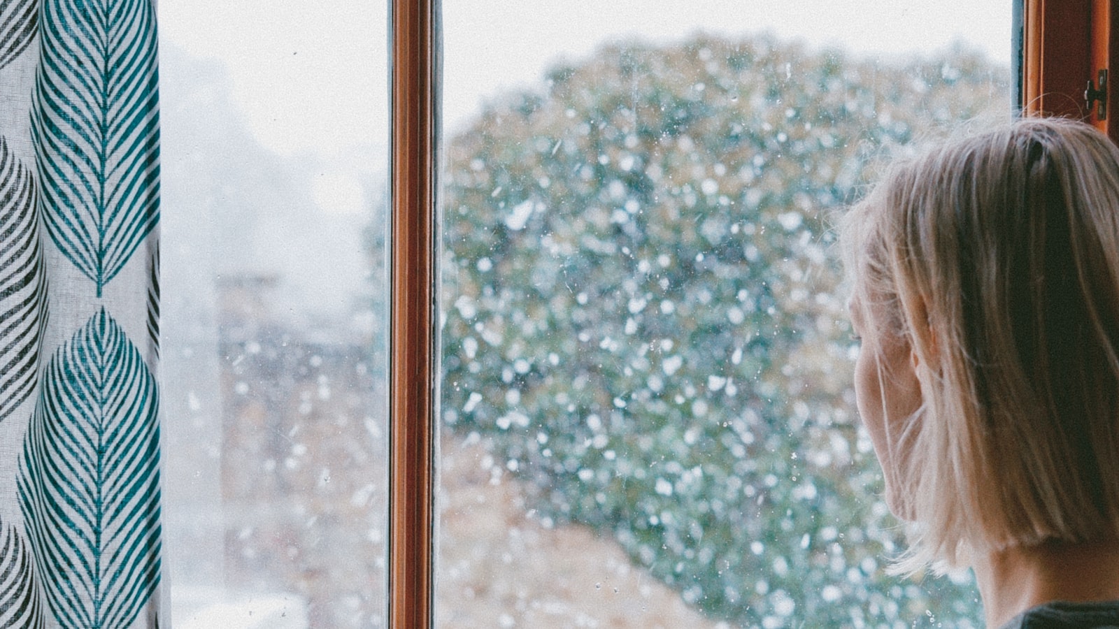 Personne regardant par une fenêtre sous la pluie