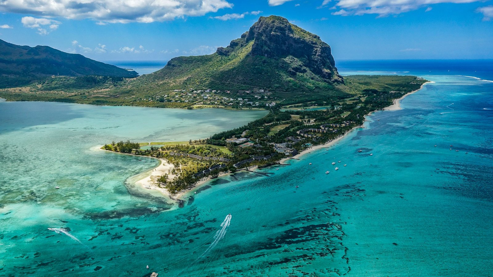 Lagon turquoise bordé de cocotiers sur la côte de l'île Maurice, avec les montagnes de l'intérieur en arrière-plan