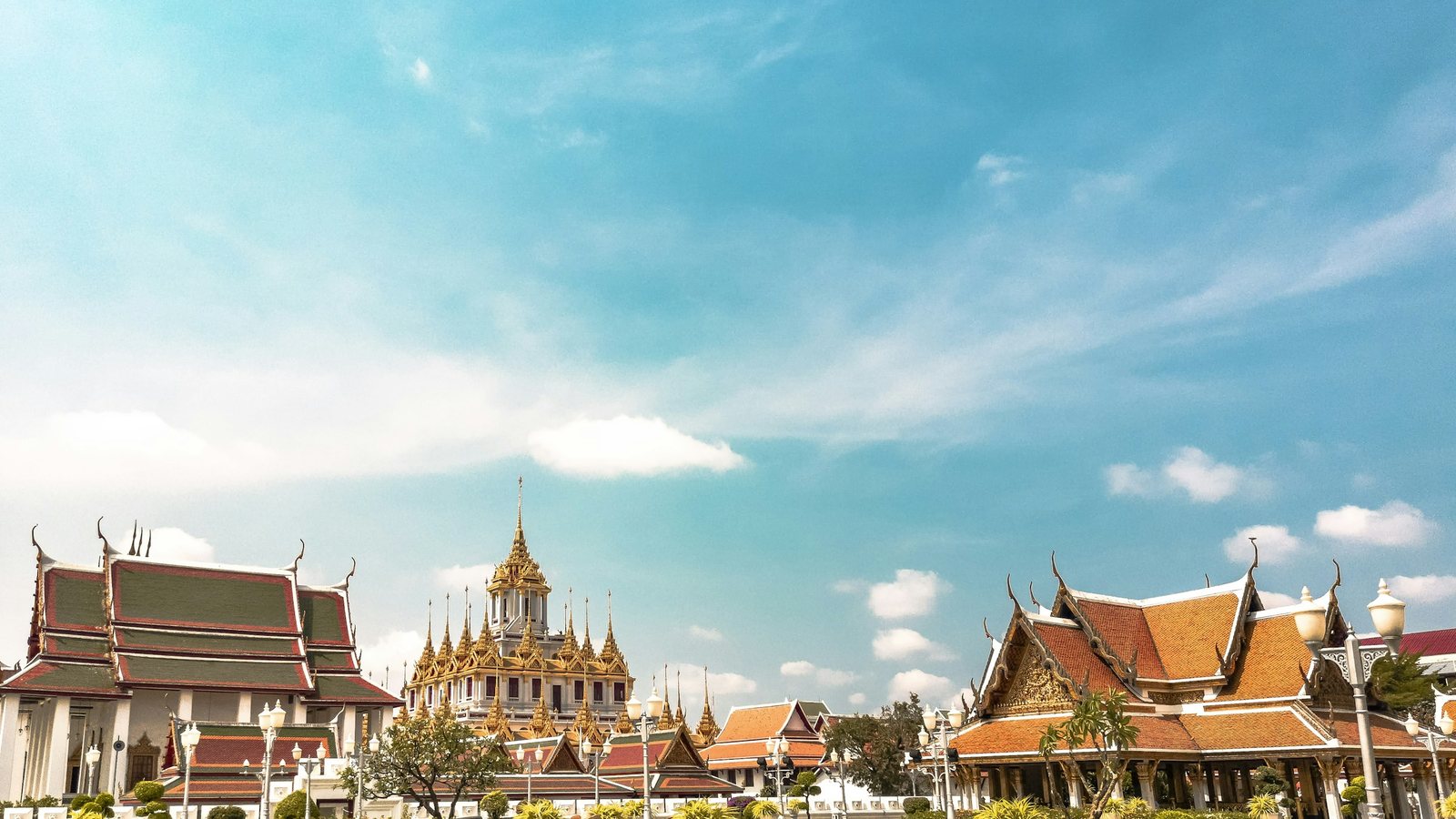 Les toits étagés et la flèche dorée des temples de Bangkok sous un ciel bleu