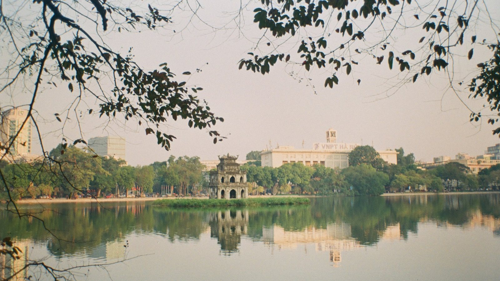 Le lac Hoan Kiem à Hanoï, avec la tour de la Tortue au centre et les bâtiments de la ville en arrière-plan
