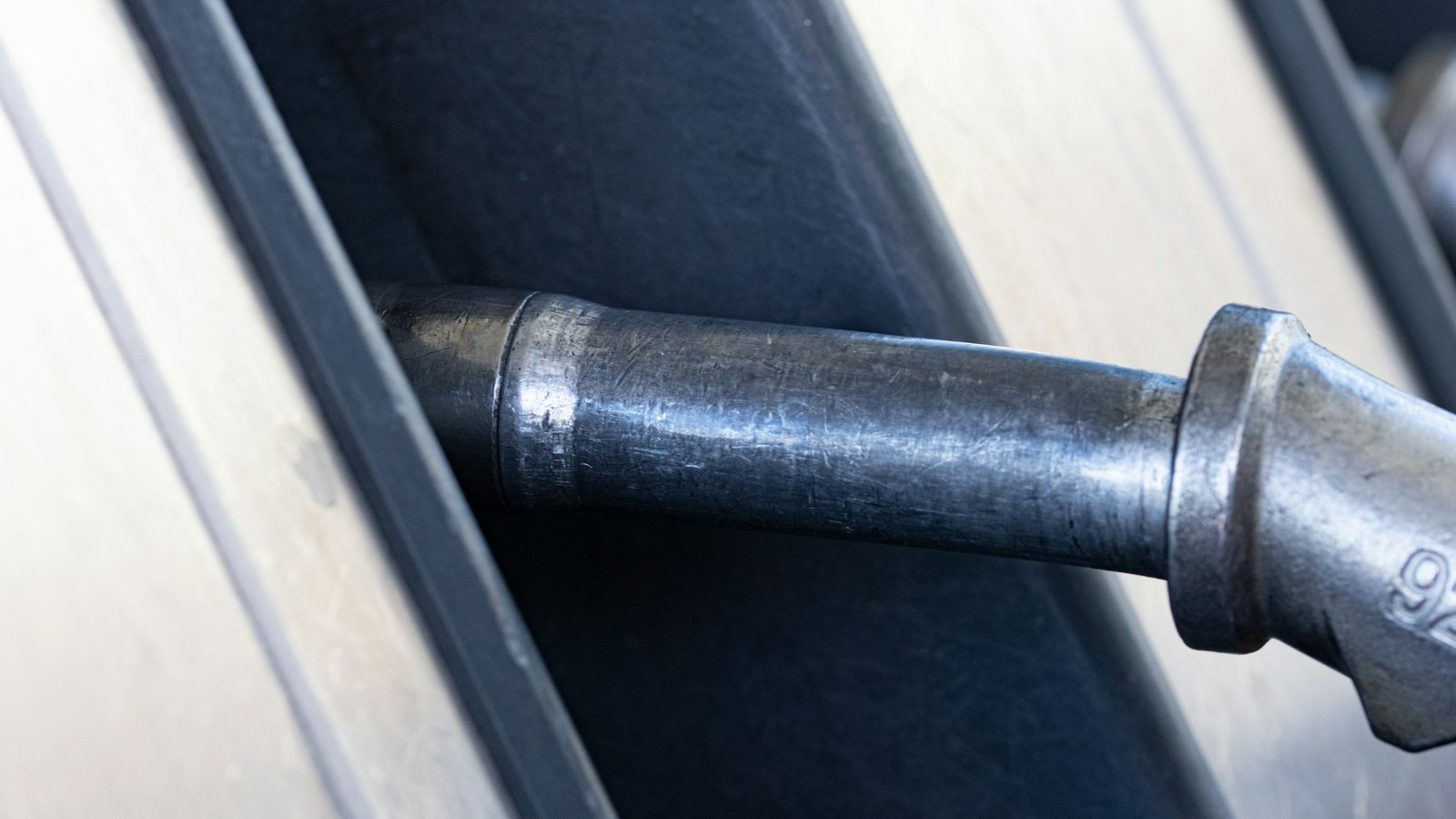 Gros plan d'un pistolet de pompe à essence inséré dans le réservoir d'un véhicule
