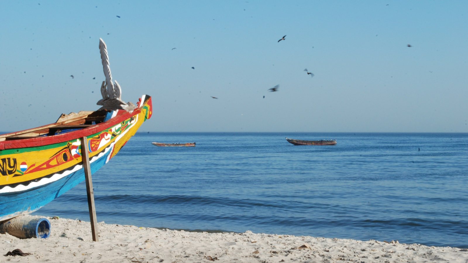 Une pirogue colorée échouée sur le sable