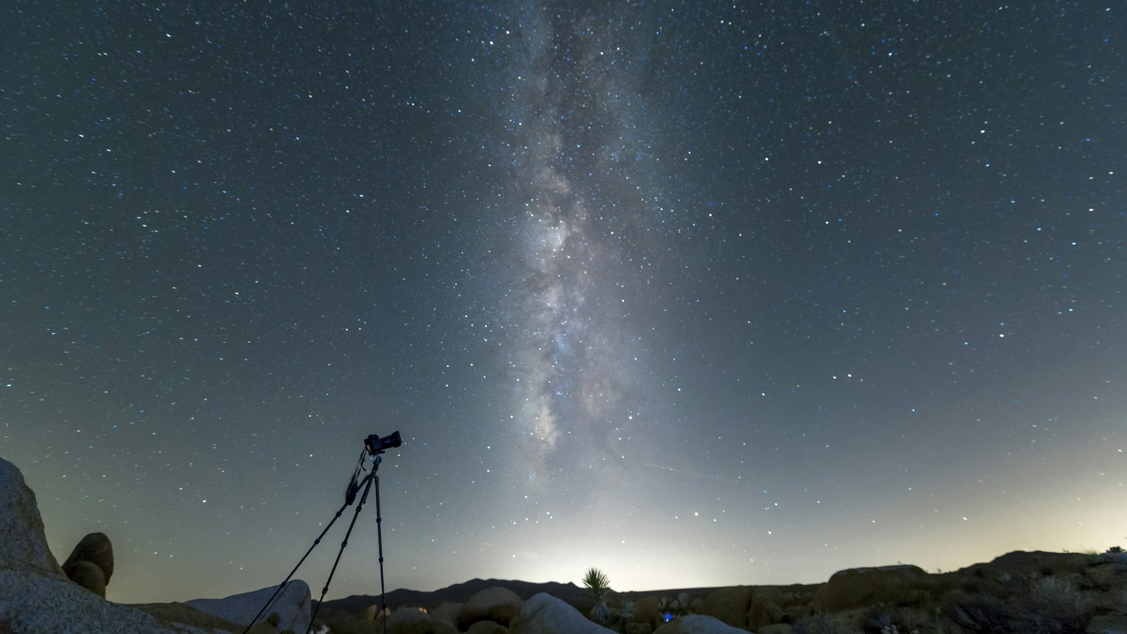 Petit télescope automatisé posé sur son trépied face à un ciel de fin de nuit, la Lune basse au-dessus de l'horizon