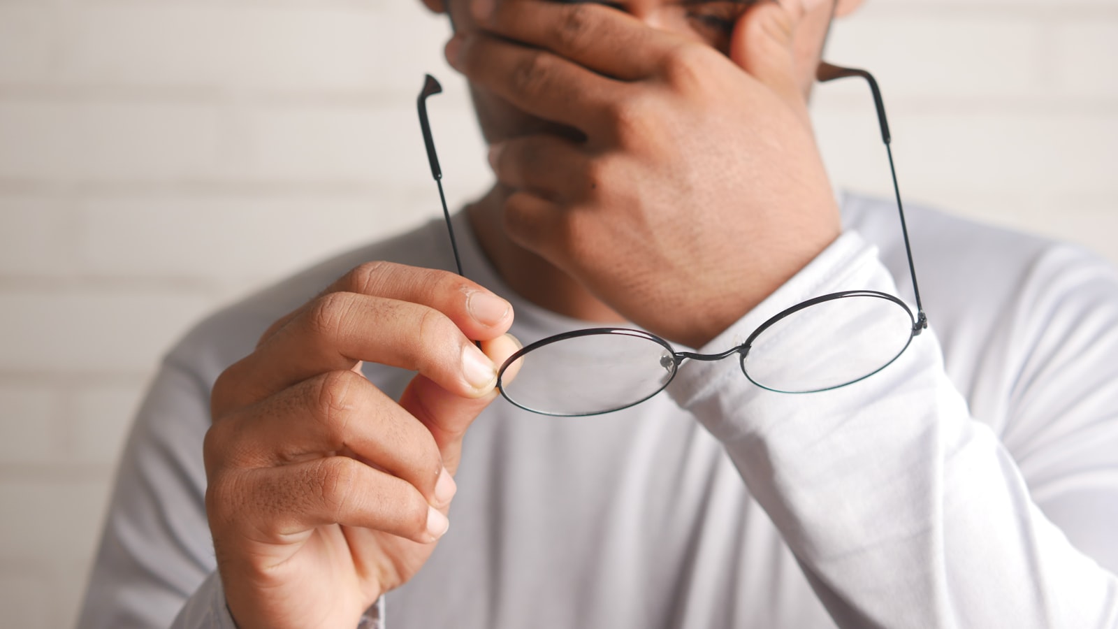 Personne fatiguée tenant ses lunettes