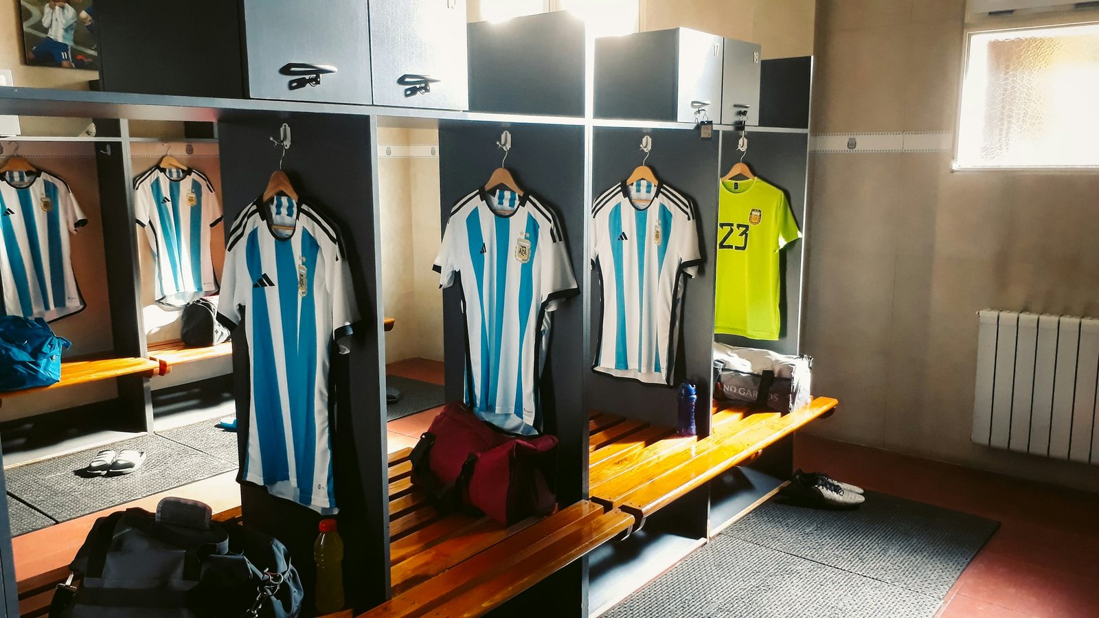 Vestiaire de football vide, maillots suspendus aux casiers et bancs en bois